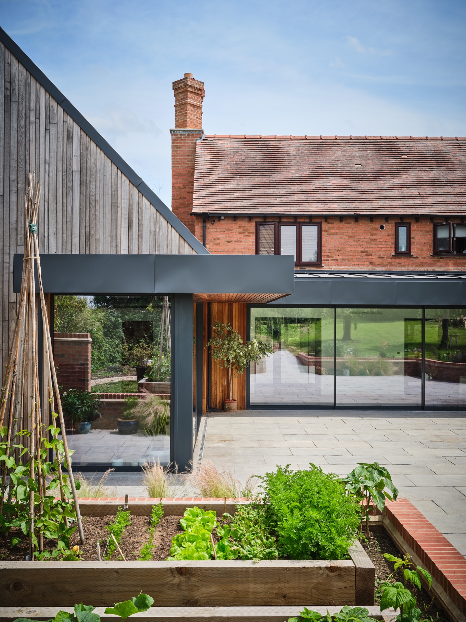 The garden with raised vegetable beds in the foreground &mdash; the glazed link and new extension beyond, the original house behind