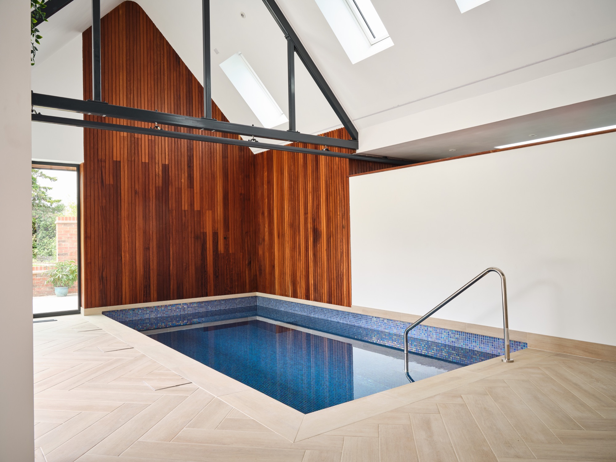 The pool gable end &mdash; trailing plants on the steel truss, terracotta door, poolside limestone surround