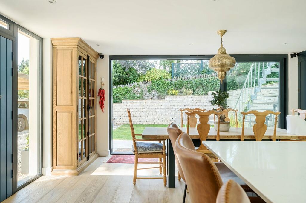 The kitchen and dining space opening through full-height glazing to the garden